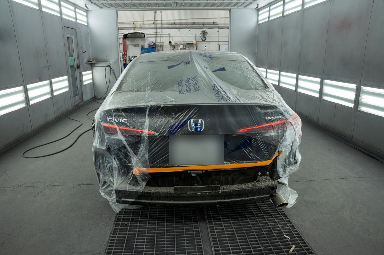 Rear of a masked Honda Civic in the paint booth