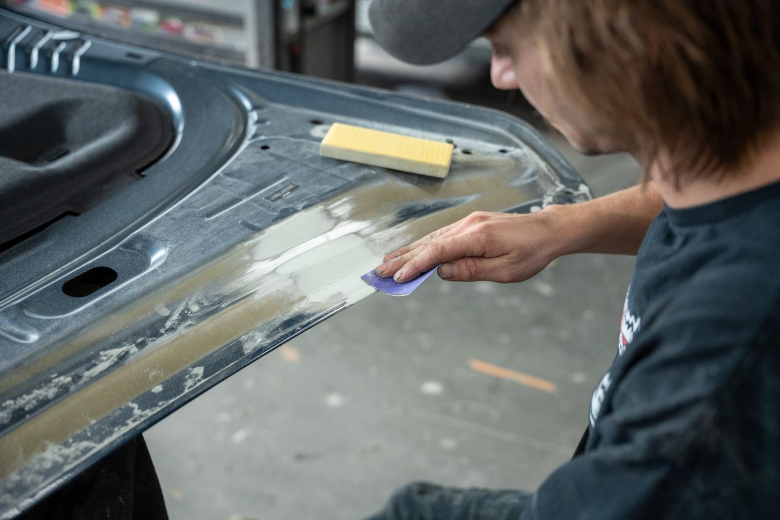 Technician hand sanding a body panel