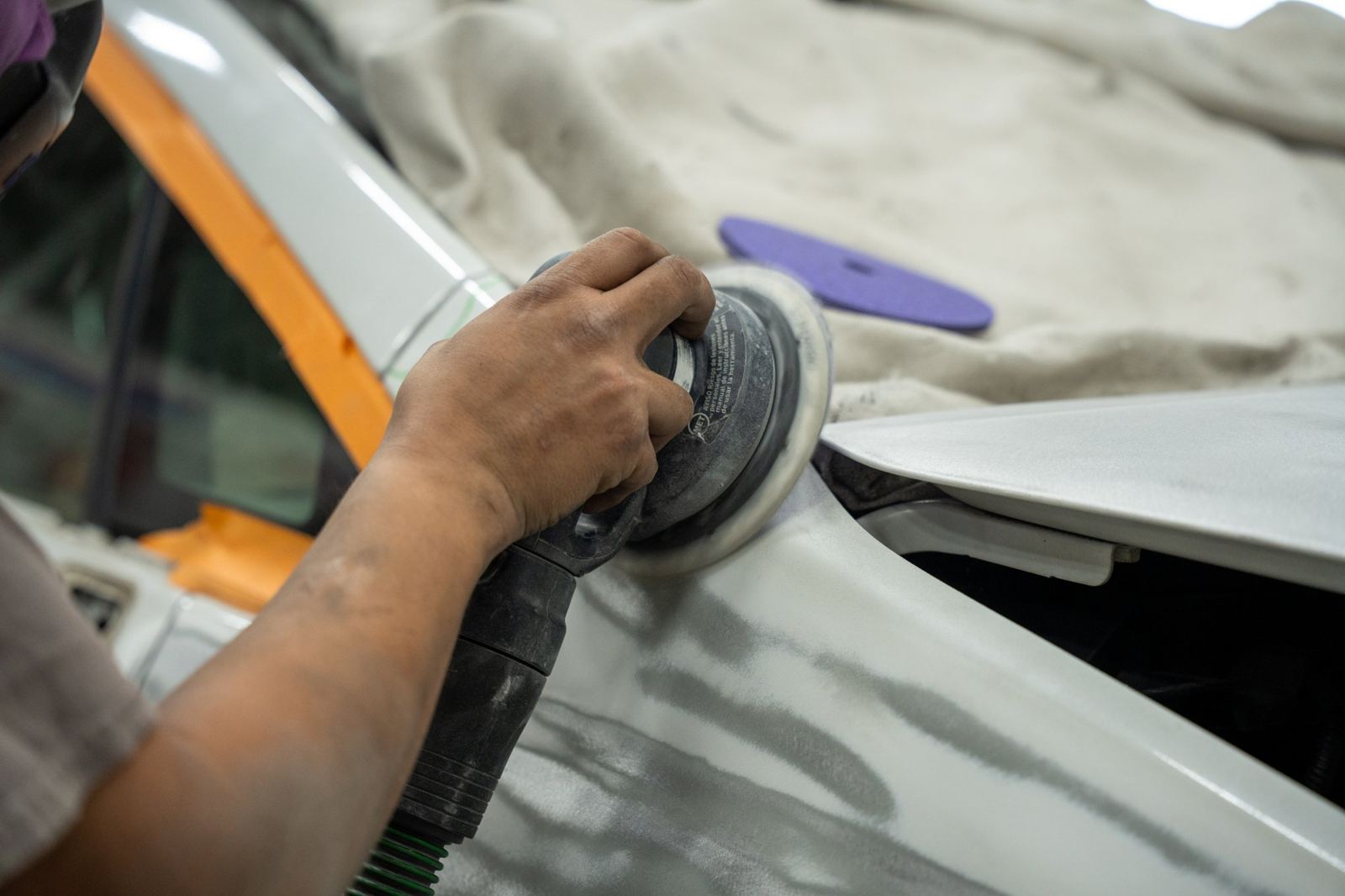 Close-up of a sander on a primed fender